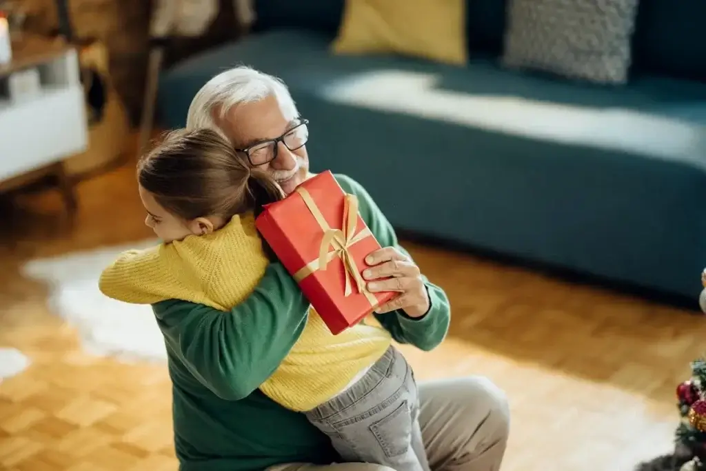 grateful-little-girl-embracing-her-grandfather-while-receiving-christmas-present-home-min