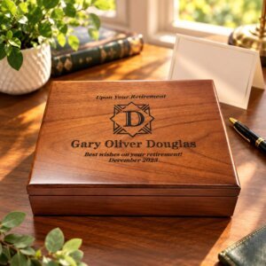 Personalized wooden retirement keepsake box with elegant engraving, displayed on a warm wooden desk with greenery and a gift card.